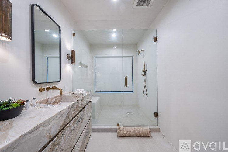 A bathroom with a marble countertop and a glass shower stall.