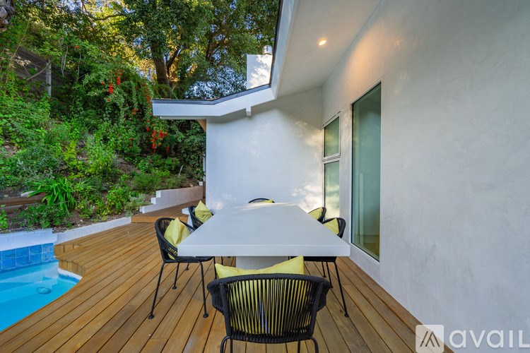 A white table with four chairs is on a wooden deck.