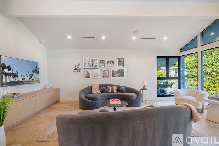 A living room with a grey couch and a painting on the wall.
