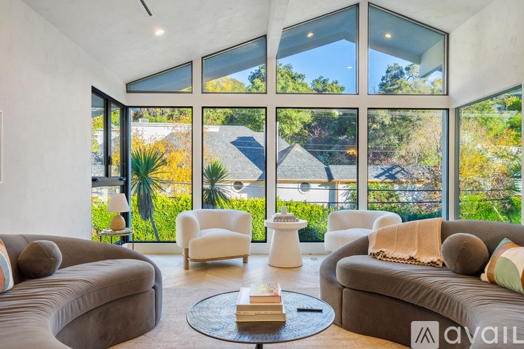 A living room with a large window and a view of a house and trees.