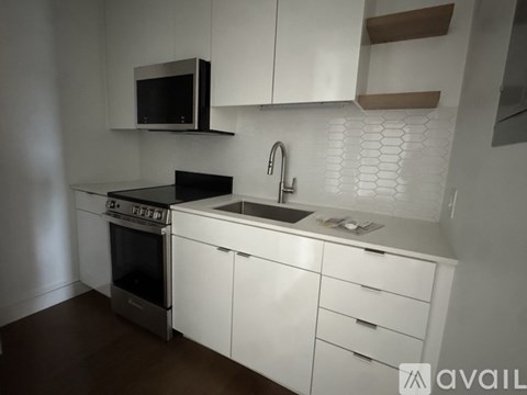 A kitchen with white cabinets and a black microwave.