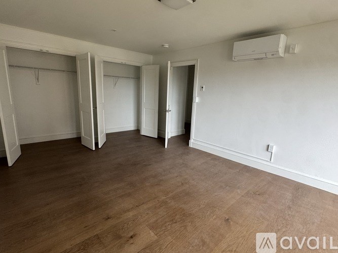 A room with wooden flooring and three open closets.