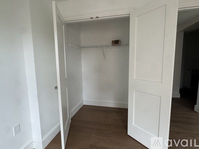 A white door is open to a room with a wooden floor.