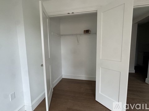 A white door is open to a room with a wooden floor.