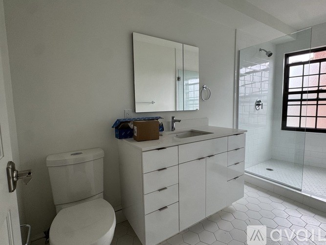 A white bathroom with a toilet, sink, and mirror.