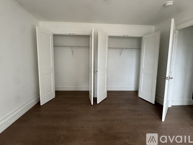 A room with white doors and brown flooring.