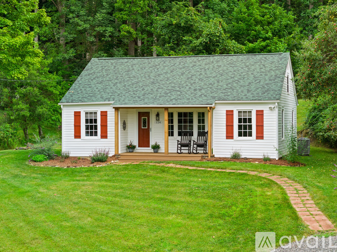 A small white house with a green roof and red shutters.