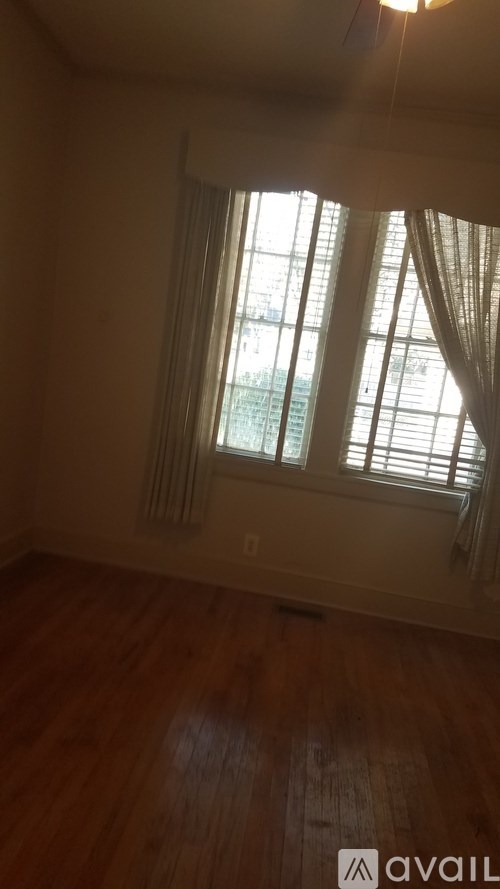 A room with wooden floors and a window with white curtains.