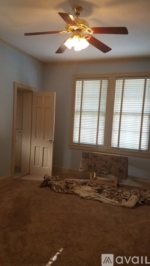 A room with a ceiling fan and a window with blinds.