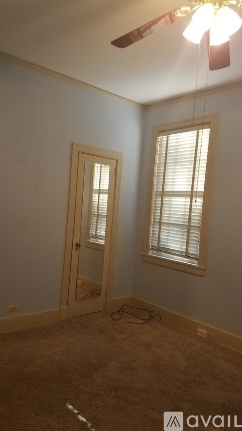 A room with a brown carpet and a ceiling fan.