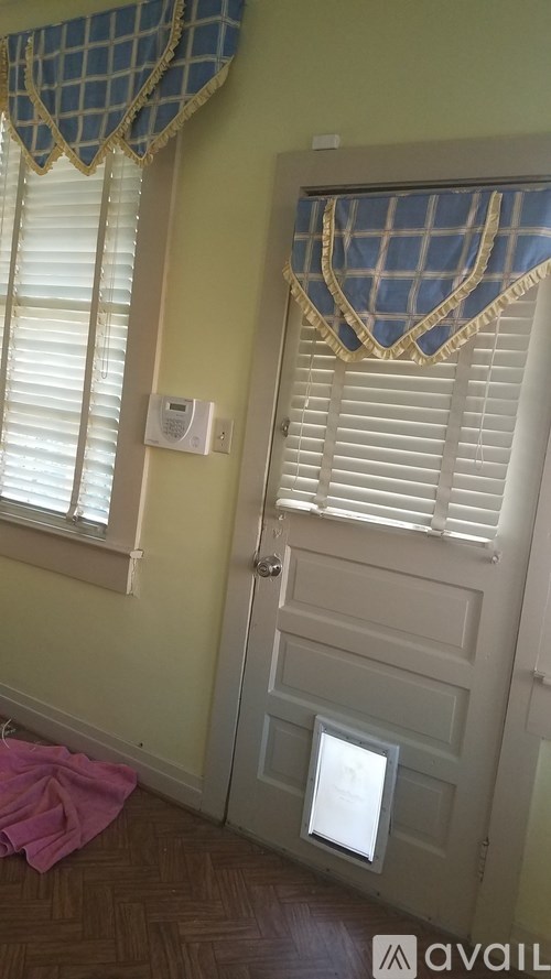 A room with a door, window, and a pink towel on the floor.