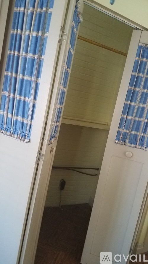A room with a white door and a blue and white checkered curtain.