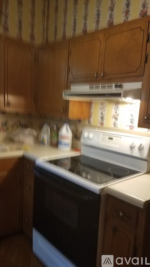 A kitchen with wooden cabinets and a white stove top oven.