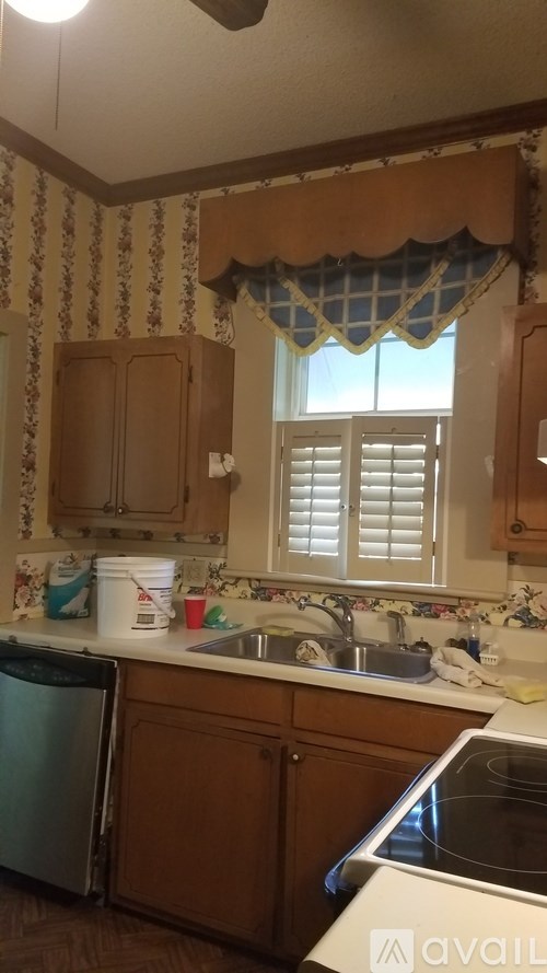 A kitchen with wooden cabinets and a window with white blinds.