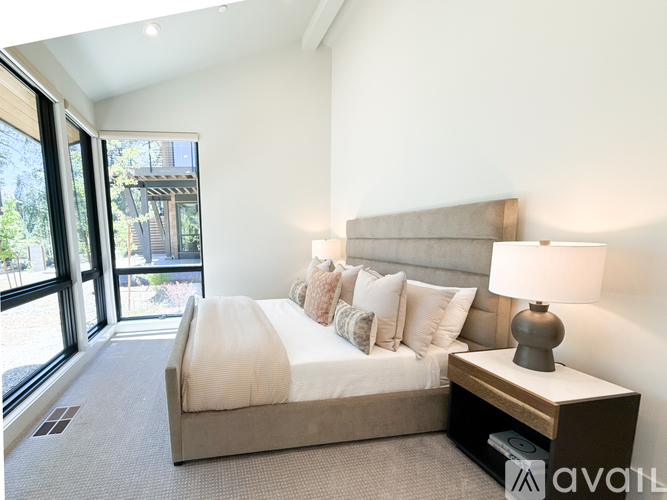 A bedroom with a large bed and a window overlooking a garden.