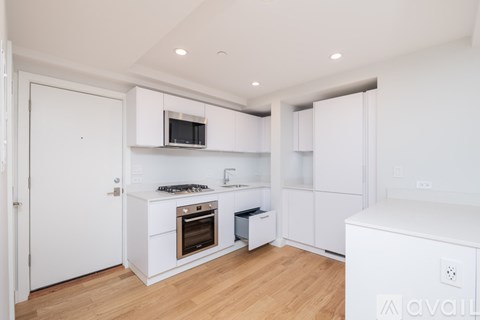 A modern kitchen with white cabinets and a wooden floor.