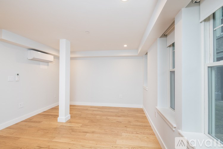 A spacious room with wooden flooring and white walls.