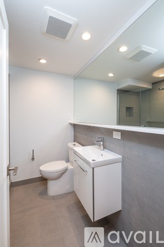 A bathroom with a toilet, sink and mirror.