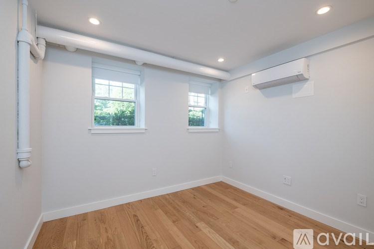 A room with wooden floors and two windows.