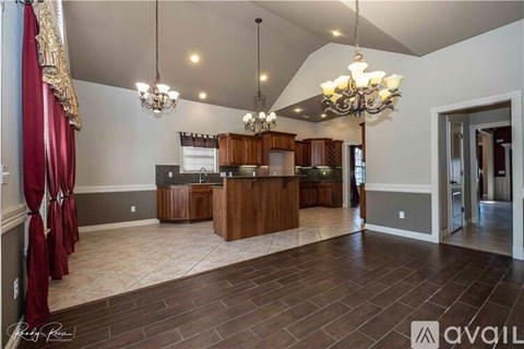 A spacious kitchen with a center island and a dining area with a chandelier.