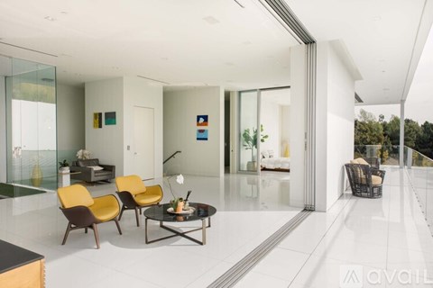 A modern living room with a glass table and yellow chairs.