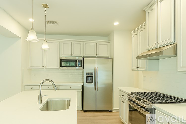 A kitchen with a stainless steel refrigerator and a white sink.