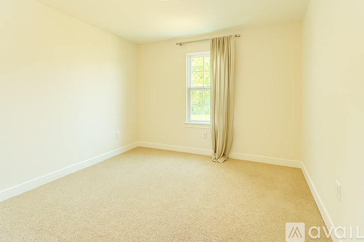A room with a carpeted floor and a window with curtains.