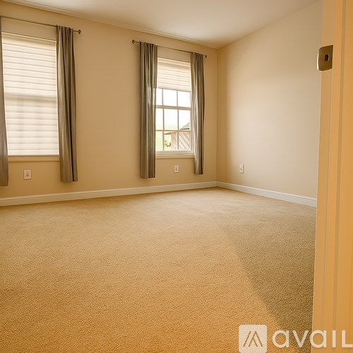 A room with beige carpet and a window with curtains.