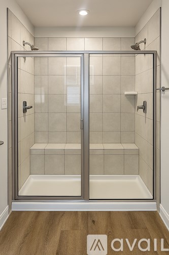 A glass shower stall with a wooden floor and a glass door.