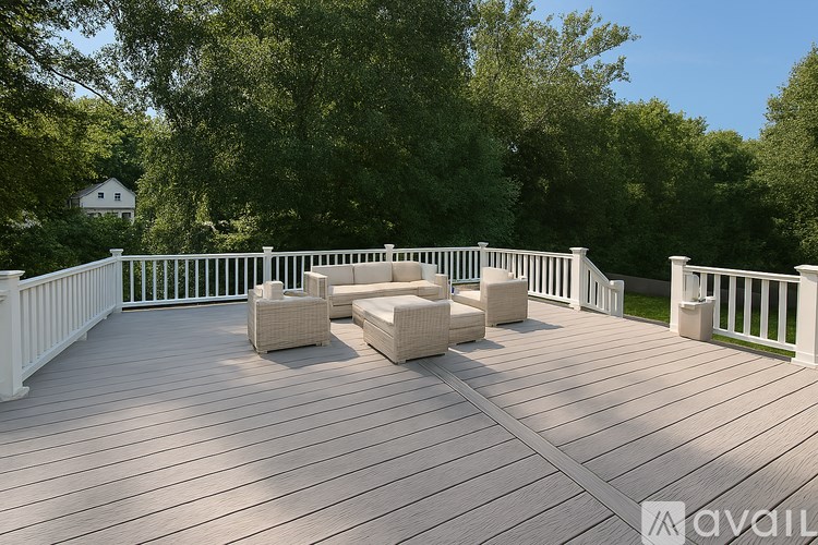A wooden deck with white railings and a white house in the background.