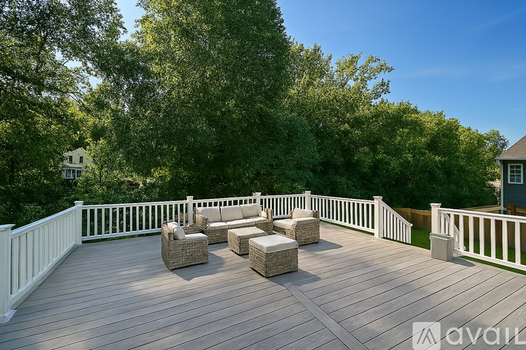A deck with white railings and wicker furniture.