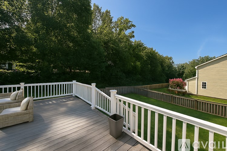 A deck with white railings and a white wicker chair.