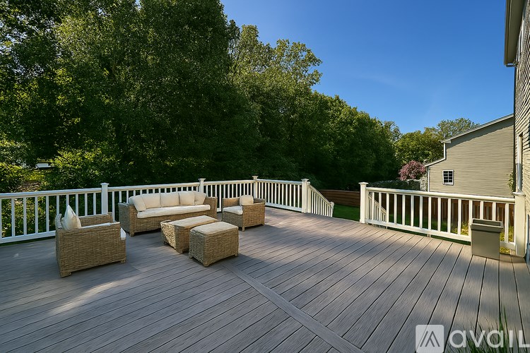A wooden deck with a white railing and furniture.