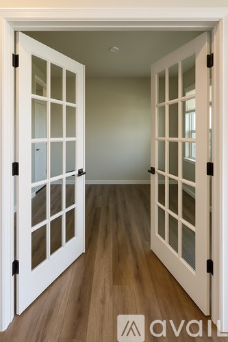 A hallway with two white doors and wooden floors.