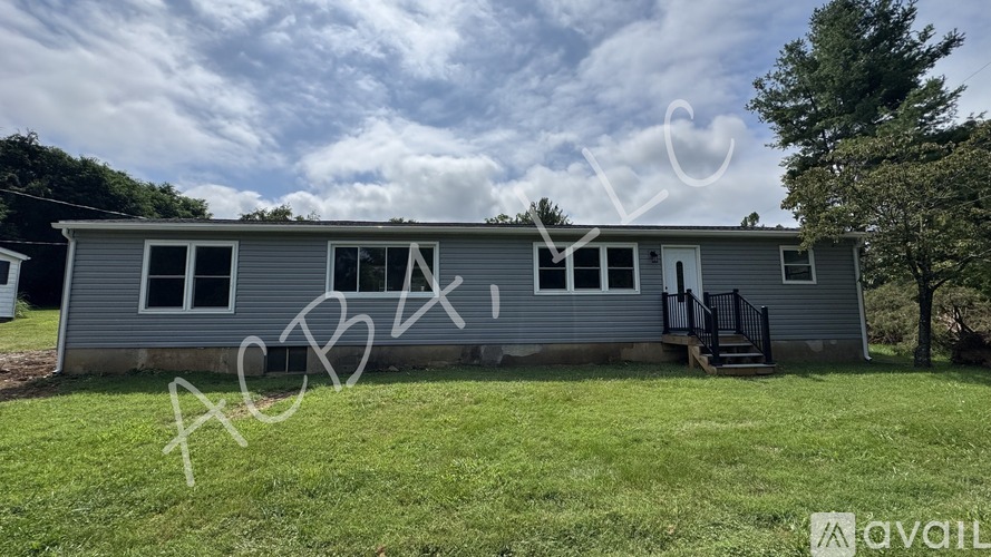 A mobile home with a porch and a tree in the background.
