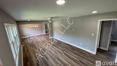 A spacious room with wooden flooring and a ceiling fan.