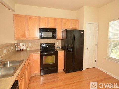 A kitchen with wooden cabinets and black appliances.