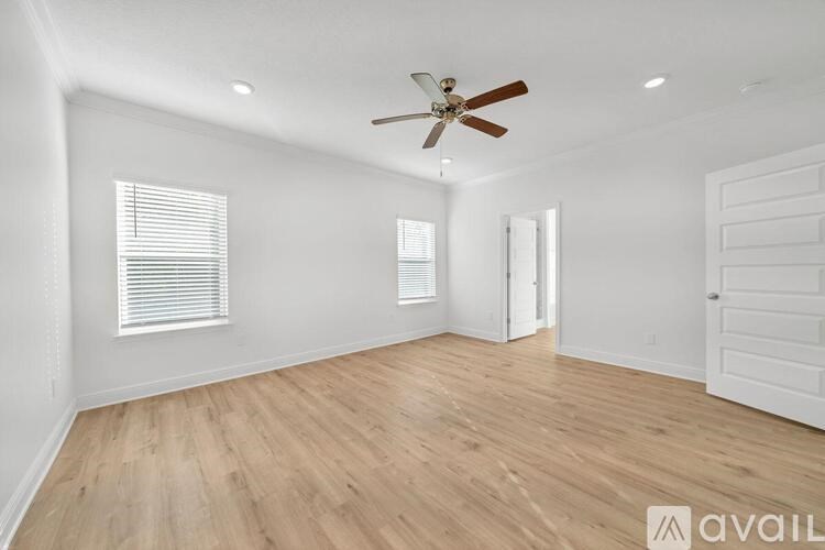 A room with a ceiling fan and wooden flooring.
