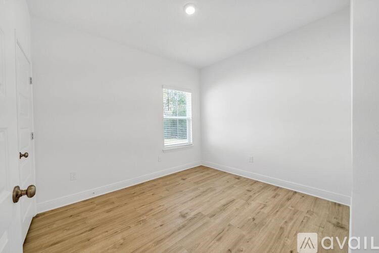 A room with wooden flooring and a window with blinds.