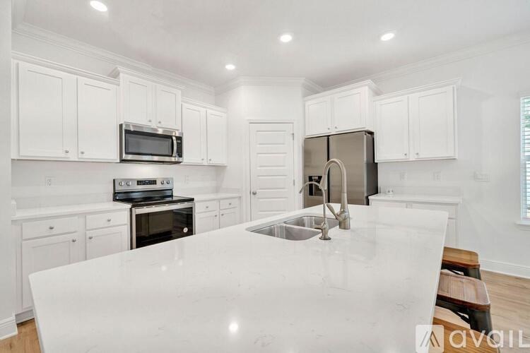 A kitchen with white cabinets and a marble countertop.