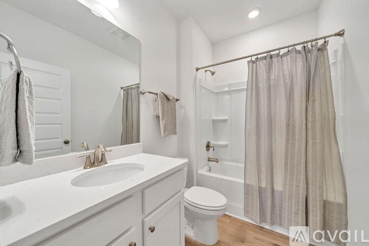 A white bathroom with a toilet, sink, and shower.