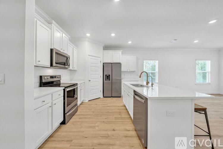 A modern kitchen with white cabinets and wooden floors.