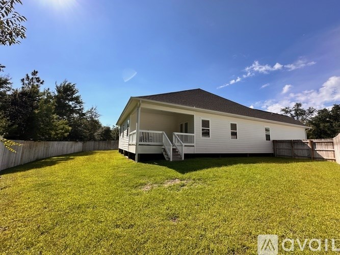 A white house with a black roof and a green lawn in front.
