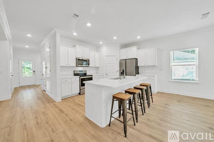 A kitchen with white cabinets and a white island with three stools.