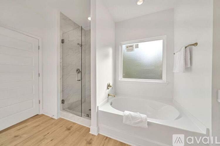 A white bathroom with a glass shower door and a white tub.