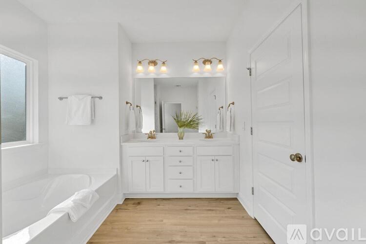 A white bathroom with a tub, sink, and mirror.