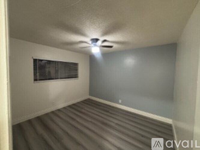 A room with a ceiling fan and a window with blinds.