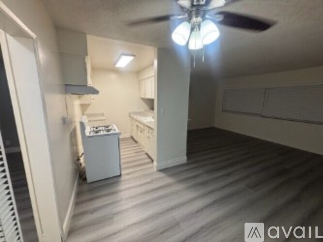 A room with a ceiling fan and a bed.