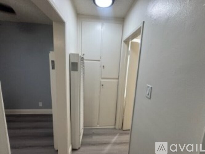 A hallway with a door on the right and a wall-mounted refrigerator on the left.
