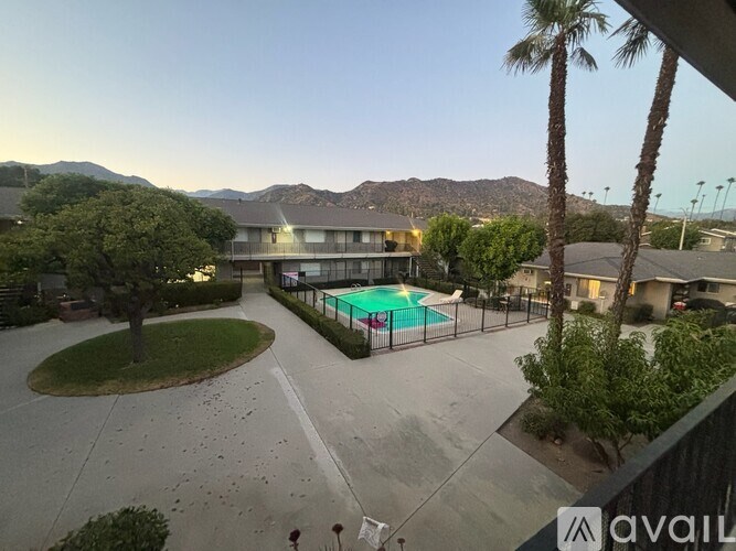 A pool surrounded by a fence and a mountain range in the background.